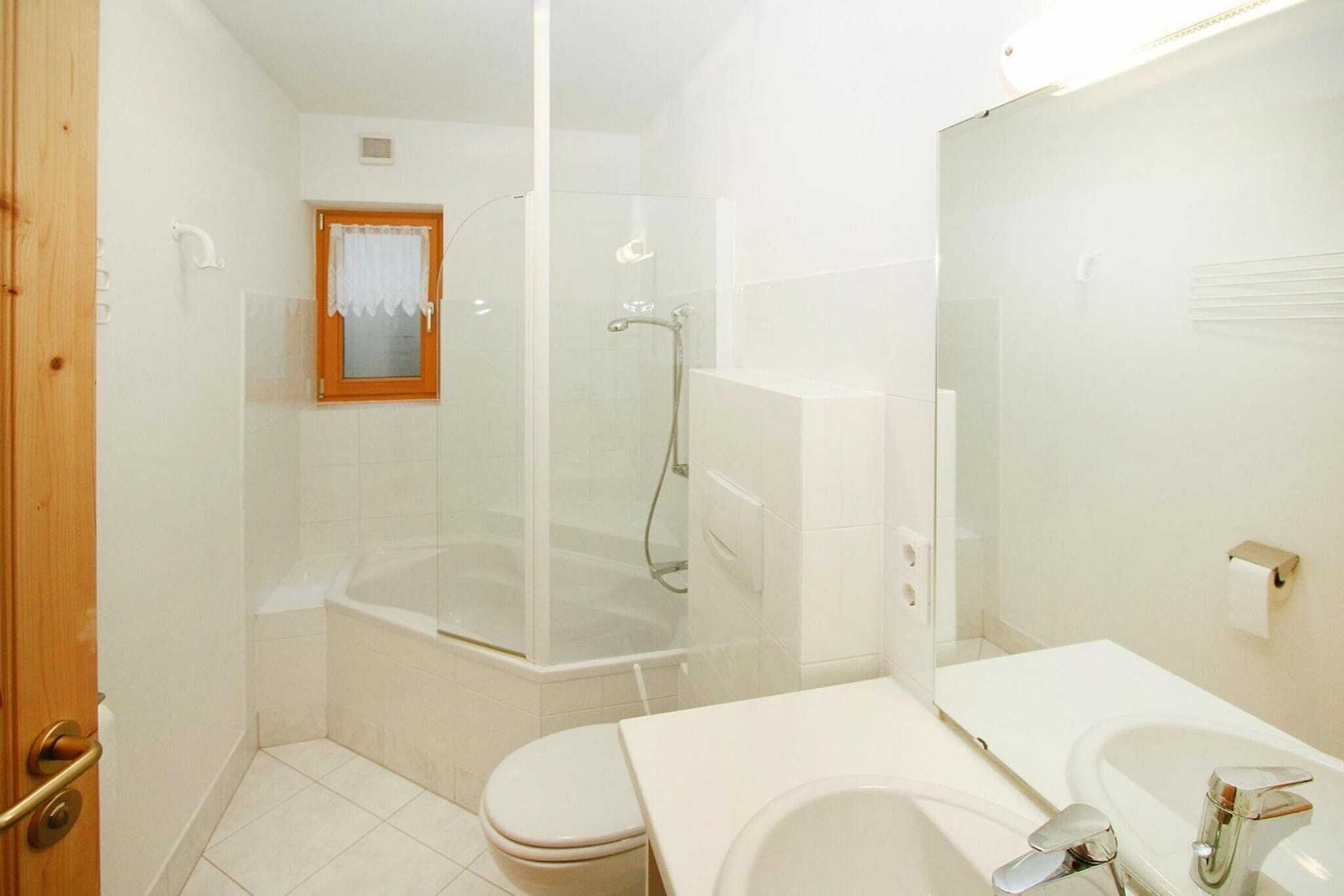 Ein Badezimmer mit einer Duschkabine, einer weißen Toilette und einem Waschbecken mit Spiegel.