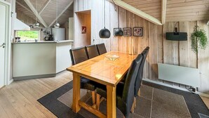 A dining area with a wooden table and chairs, a kitchen in the background, and a wooden ceiling. - Beautiful home in Blåvand with WiFi (Blåvand)