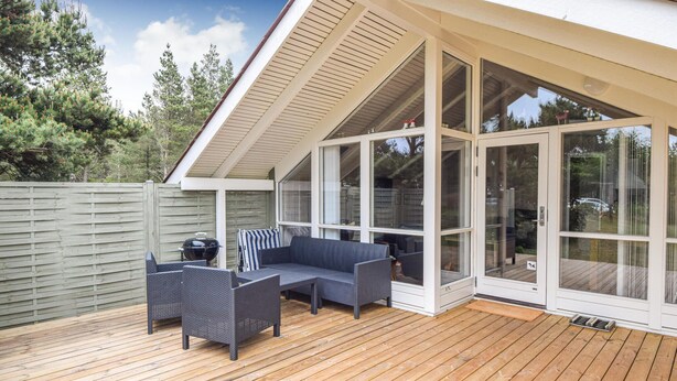 A covered outdoor seating area with a wooden deck, a grill, and a sofa. - Beautiful home in Blåvand with WiFi (Blåvand)