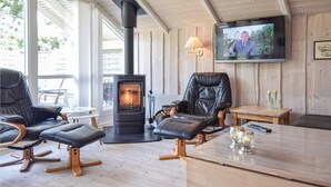 A cozy living room with a fireplace, leather chairs, a TV, and a wooden table. - Beautiful home in Blåvand with WiFi (Blåvand)