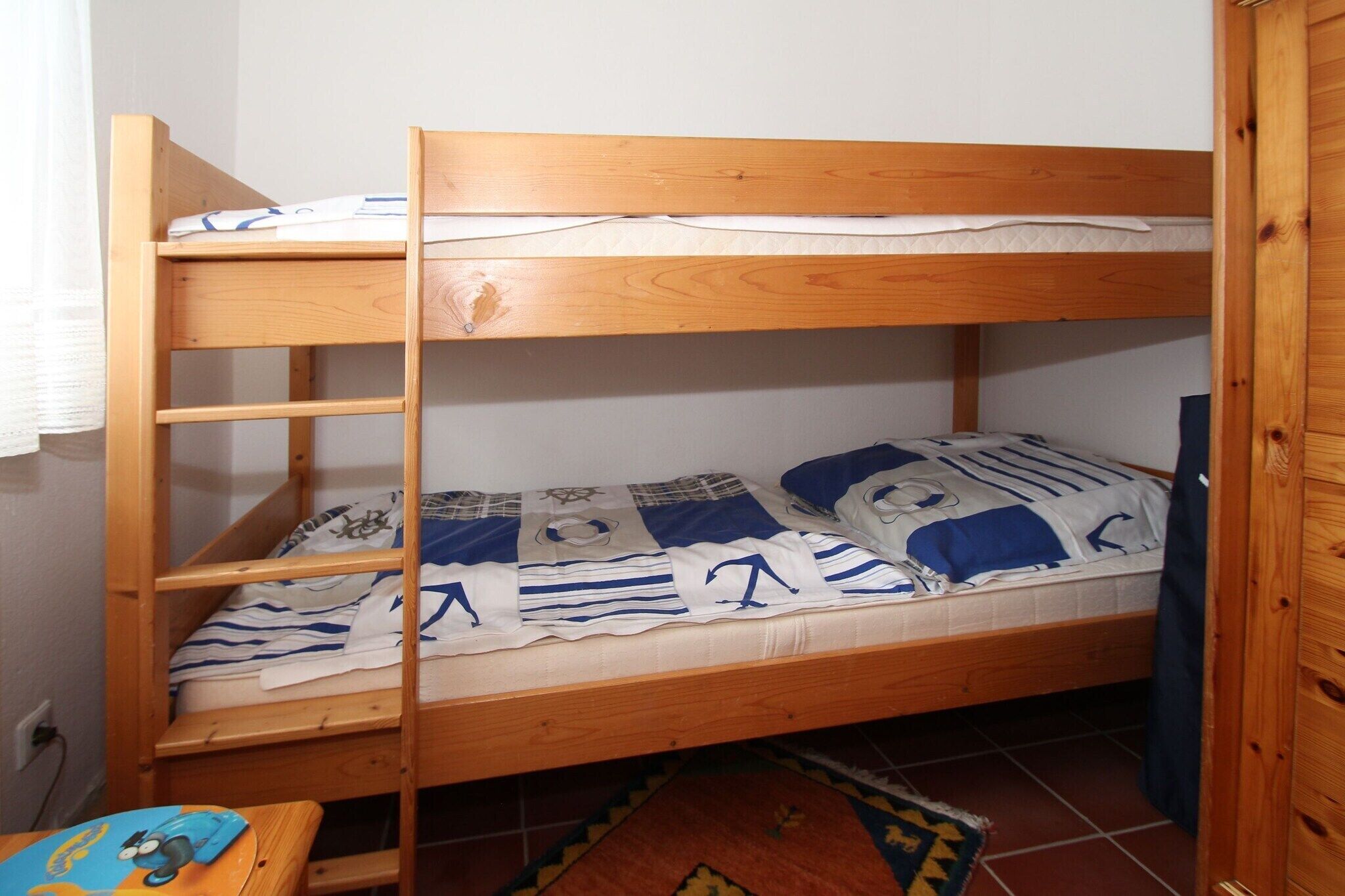 A bunk bed with a lower bunk and a top bunk, both with wooden frames.