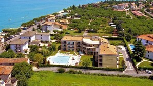 A coastal residential area with a large building featuring a swimming pool, surrounded by greenery and residential houses.