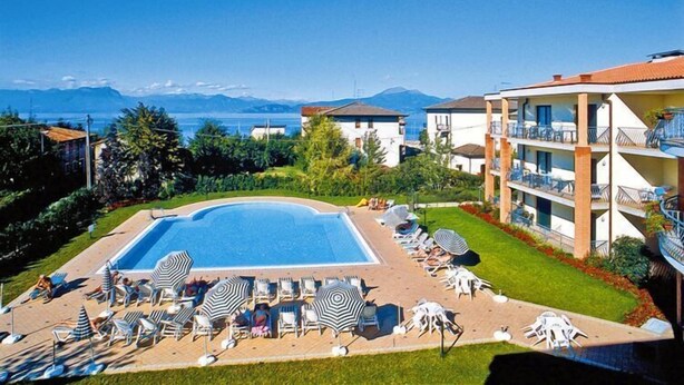 A hotel with a swimming pool, sun loungers, and a view of the sea.