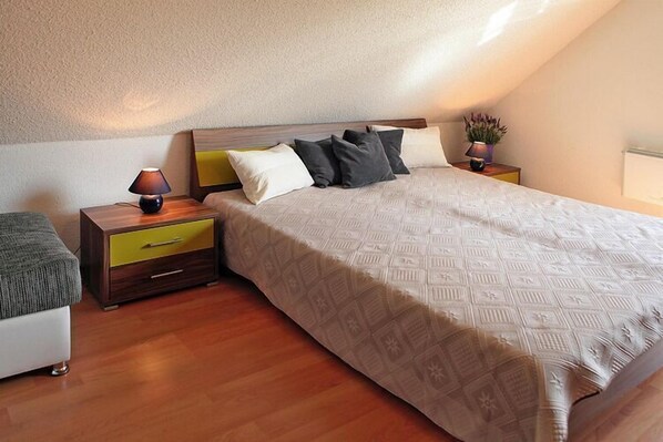 Un dormitorio con cama, mesitas de noche, una lámpara y una planta en maceta.