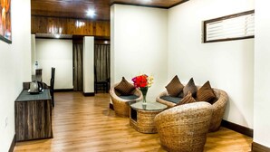 Una habitación con muebles de mimbre, una mesita con un florero y una cafetera sobre una mesa de madera.