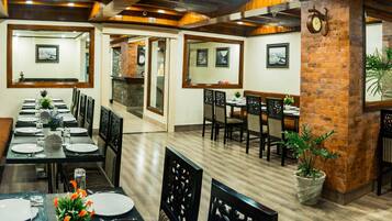 Un restaurante con una larga mesa de comedor, múltiples sillas y una pared de ladrillo decorativa.