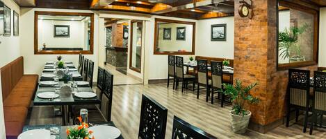 A restaurant with a long dining table, multiple chairs, and a brick accent wall.