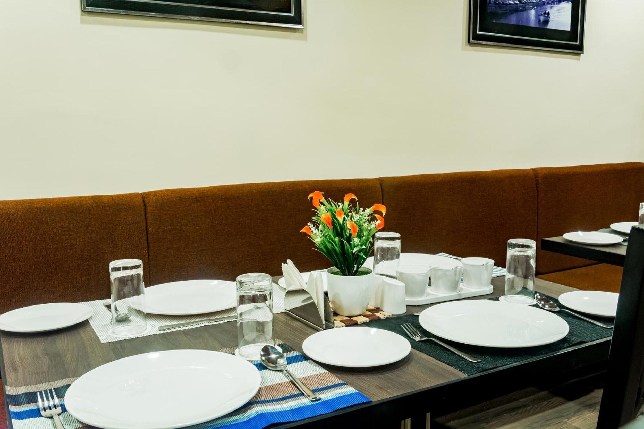 A dining table set with plates, cutlery, glasses, and a centerpiece of orange flowers.