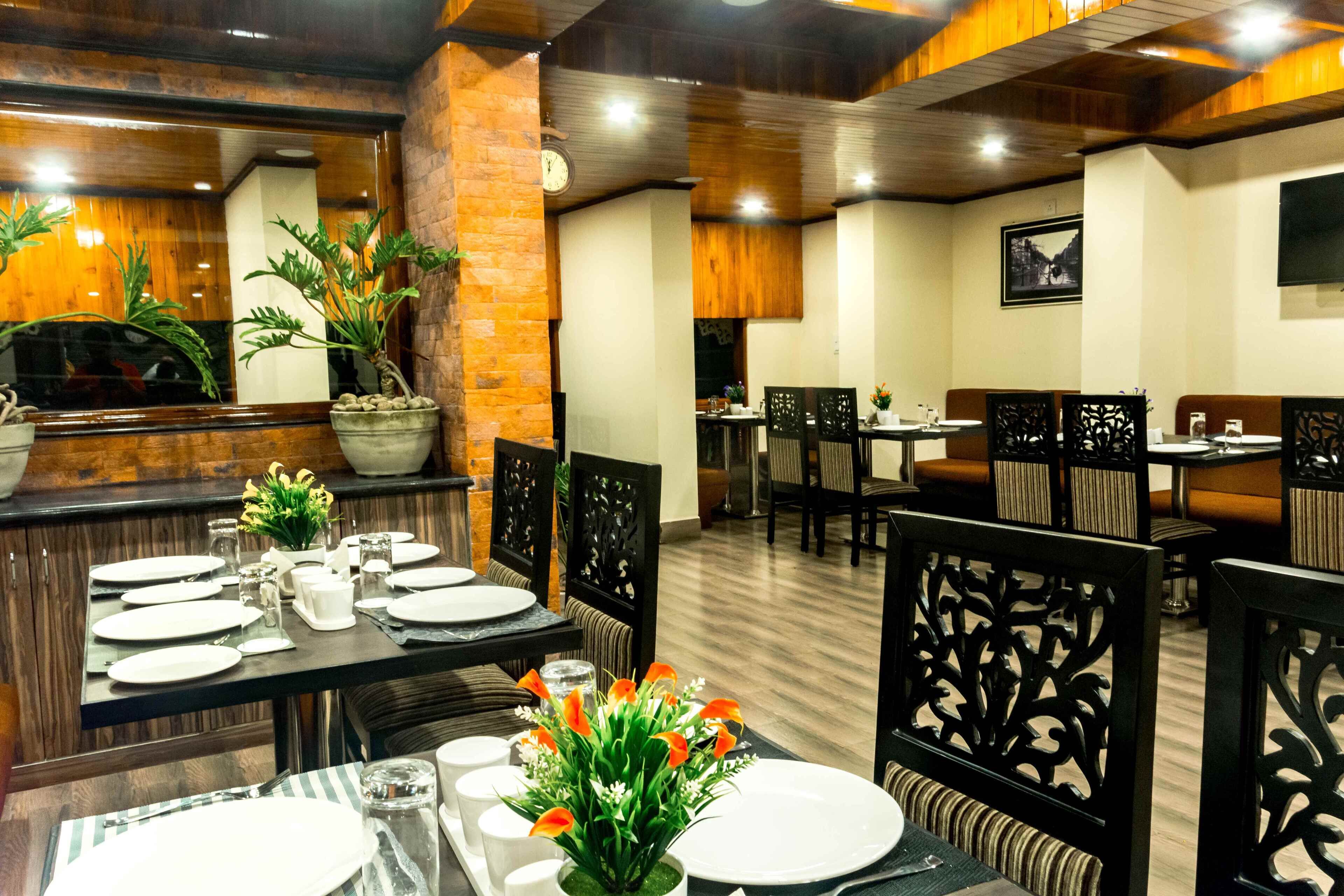 A restaurant with wooden decor, tables set for dining, and potted plants.