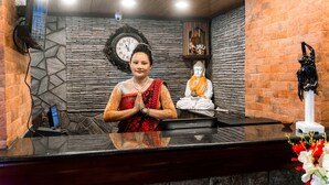 Zona de recepción con recepcionista, un reloj y una estatua de Buda.
