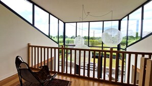 Un balcon spacieux avec une balustrade en bois, une chaise et une vue sur la campagne.