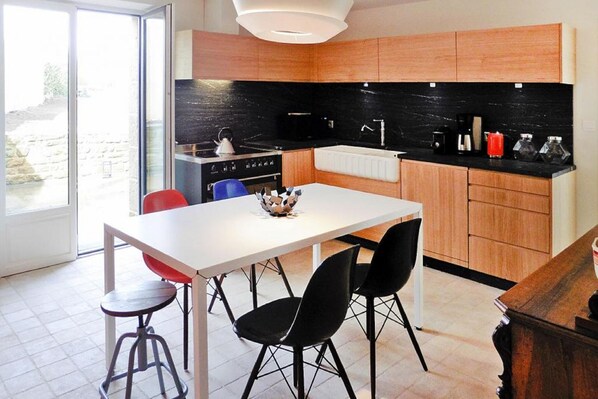 A modern kitchen with wooden cabinets, a black countertop, and a white dining table with black chairs.
