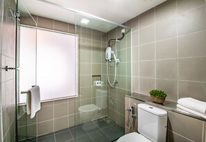 Ein modernes Badezimmer mit Duschkabine aus Glas, Toilette und Waschbecken mit Zimmerpflanze.