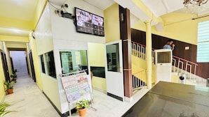 A lobby with a reception desk, a digital display, a staircase, and potted plants. - Hotel Holidei Inn (Golmuri)