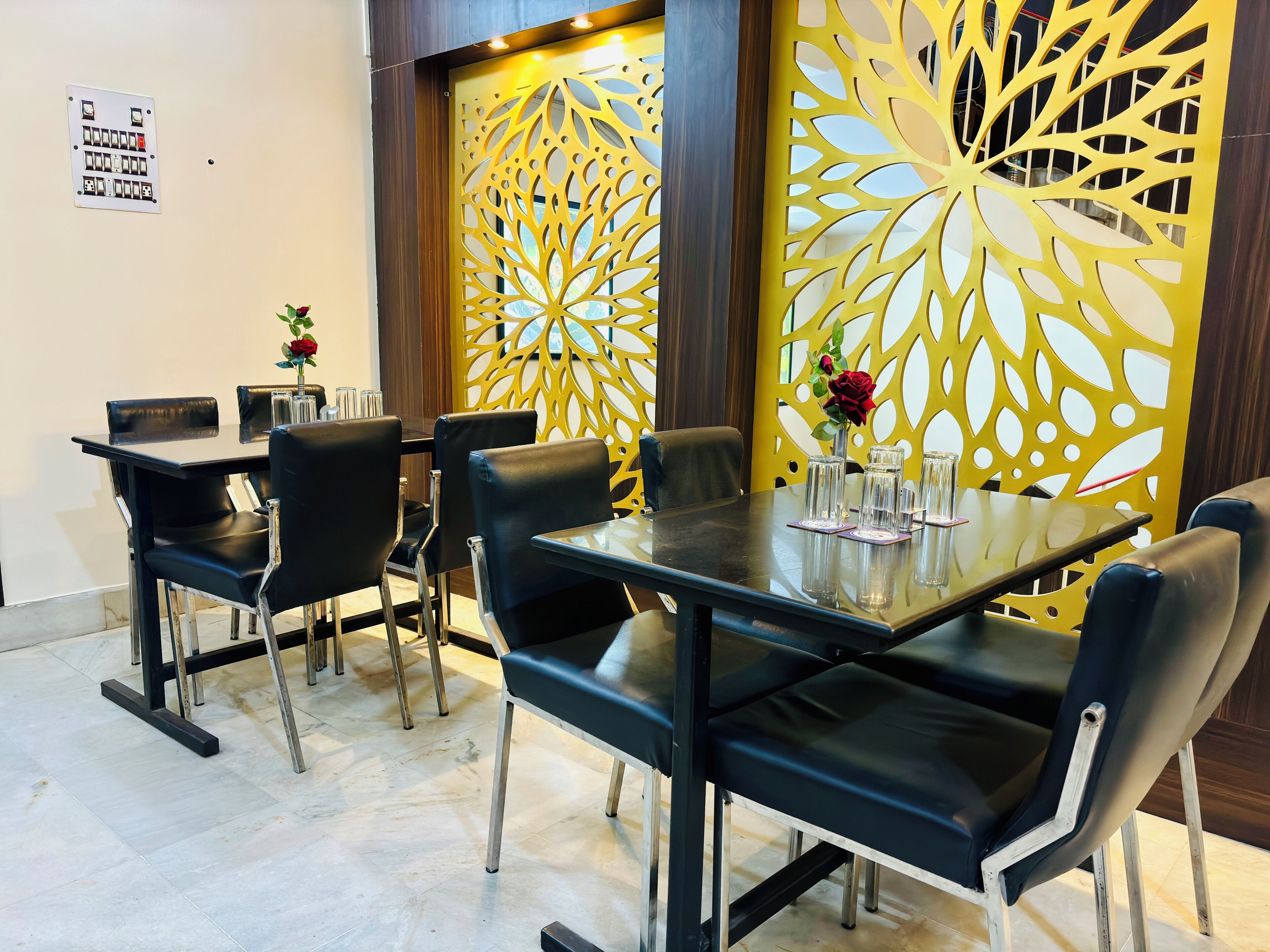 Un espace repas avec une table en verre, des chaises noires et un paravent jaune décoratif.