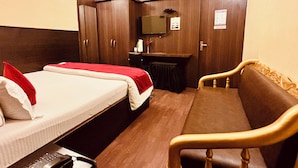 A hotel room with a bed, a sofa, a desk, and a television. - Hotel Holidei Inn (Golmuri)