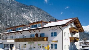 A two-story building with a sign reading "Wirtshaus" and a shop named "Nah&Frisch Markt" in front. - Apartment in Zugspitz Arena near Highline 179 (Bichlbach)