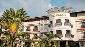 A multi-story hotel with balconies, a curved facade, and tropical plants. - Hotel TSG Grand (Port Blair)