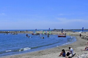 A beach with people, boats, and flags. - Cottage in Bellegarde near Camargue Reserve (Bellegarde)