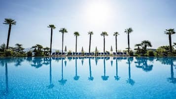 Une piscine d’un bleu éclatant, avec des chaises longues et des palmiers.