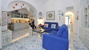 Un área de estar amplia con un sofá azul, una mesa de centro y una cocina al fondo.