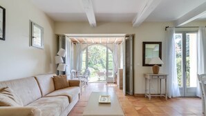 A spacious living room with a beige sofa, a coffee table, and a view through an open archway to an outdoor patio.
