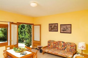 A room with a sofa, a dining table, and chairs. There are two framed pictures on the wall.