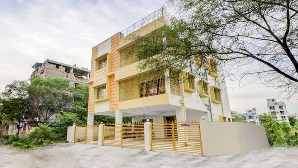 A multi-story residential building with a gated entrance, balconies, and surrounding greenery. - Treebo Trip Flama House (Baruipur)