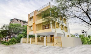 A multi-story residential building with a gated entrance, balconies, and surrounding greenery. - Treebo Trip Flama House (Baruipur)