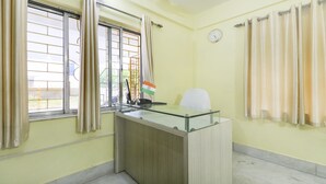 A room with a desk, a clock, and a window with curtains. - Treebo Trip Flama House (Baruipur)