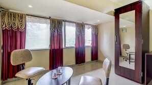 Habitació d'hotel amb un mirall gran, dues cadires, una taula petita i un armari.