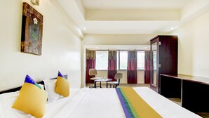 Habitació d'hotel amb un llit, dues cadires, una taula petita, una televisió i un quadre a la paret.