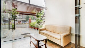 Una habitació amb un sofà beix, una taula de fusta i plantes en testos.