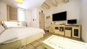 Une chambre d’hôtel avec un grand lit, une télévision, un bureau en bois et une salle de bain équipée d’un porte-serviettes.