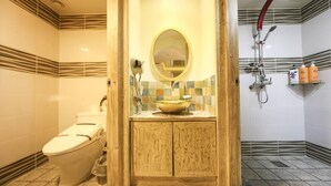 Une salle de bain comprenant des toilettes, un lavabo avec un miroir et un espace douche.