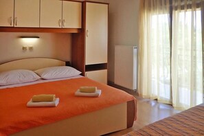 Ein Hotelzimmer mit einem großen Bett, einem Schrank, einem Heizkörper und einem Vorhangfenster.