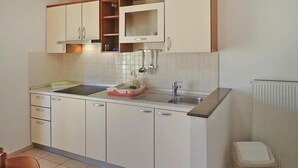 A compact kitchen with white cabinets, a built-in microwave, and a sink. - Apartment in Starigrad Paklenica, National Park (Starigrad Paklenica)