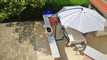 A patio area with a stone bench, a table, and a white umbrella.