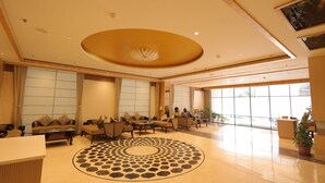 A spacious lobby with a central seating area, large windows, and a decorative floor pattern. - Hotel Costa River (Varanasi)