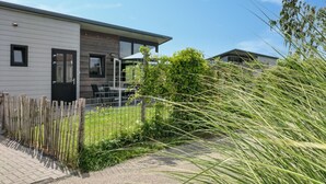 Een modern huis met twee verdiepingen, een patio, een omheind gazon en een heldere lucht.