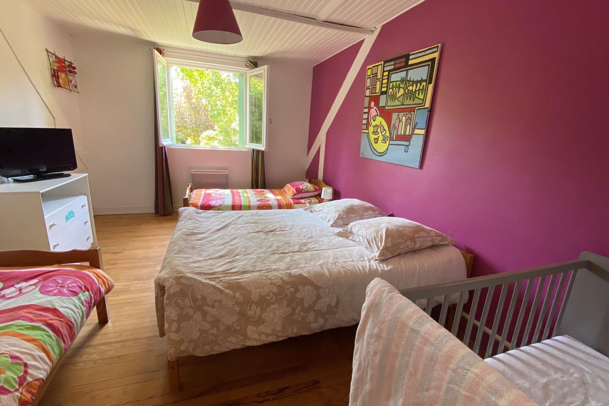 A bedroom with two beds, a television, and a window.