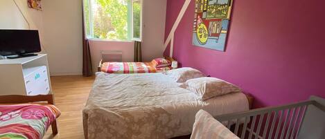 A bedroom with two beds, a television, and a window.