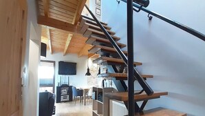 Um interior moderno com escada de madeira, televisão de tela plana e área de jantar.