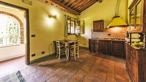 A rustic kitchen with exposed wooden beams, a tiled backsplash, and a yellow lamp. - Country House in Tuscany with Pool and Olive Grove (Santo Pietro Belvedere)