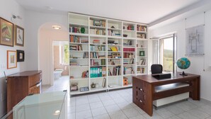 Een studeerkamer met een grote boekenkast, een bureau en een wereldbol.