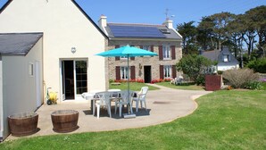 Una casa con techo solar, un patio con mobiliario exterior y un jardín bien cuidado.