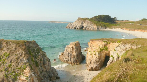 Un paisaje costero con acantilados rocosos, una playa de arena y una vista despejada del mar.