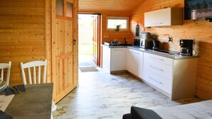 A compact kitchen with wooden walls, a dining area with a table and chairs, and a small window. - Single-story, year-round holiday home (Ustronie Morskie)