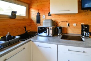 A compact kitchen with a microwave, toaster, coffee maker, and a sink.