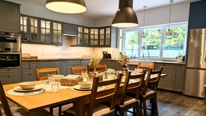 A modern kitchen with grey cabinets, stainless steel appliances, and a dining area with wooden chairs and a table set for four. - Spacious holiday apartment with sauna, Kolobrzeg (Kolobrzeg)